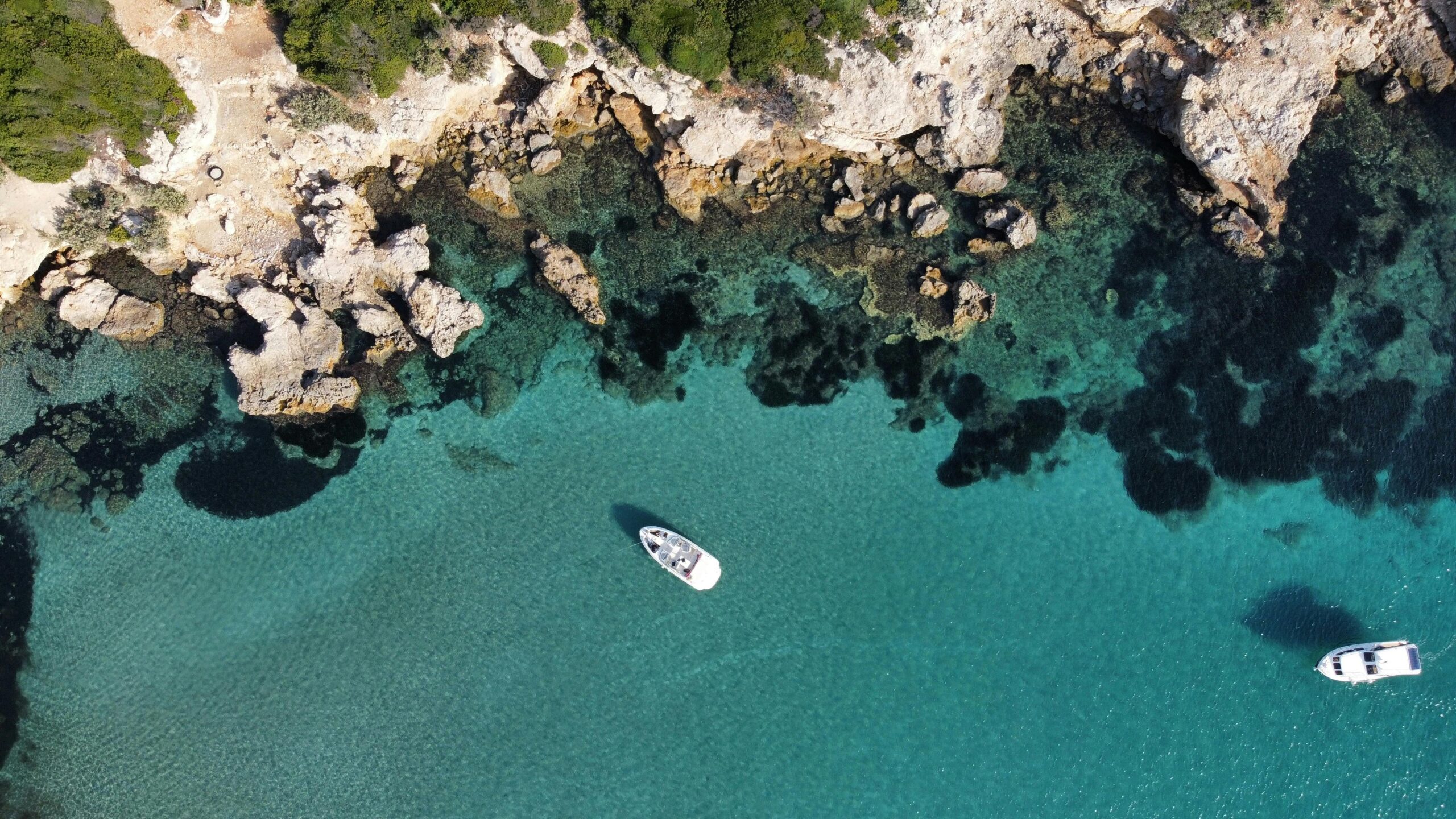Aerial photography of two white boats on the ocean near rocky coastline