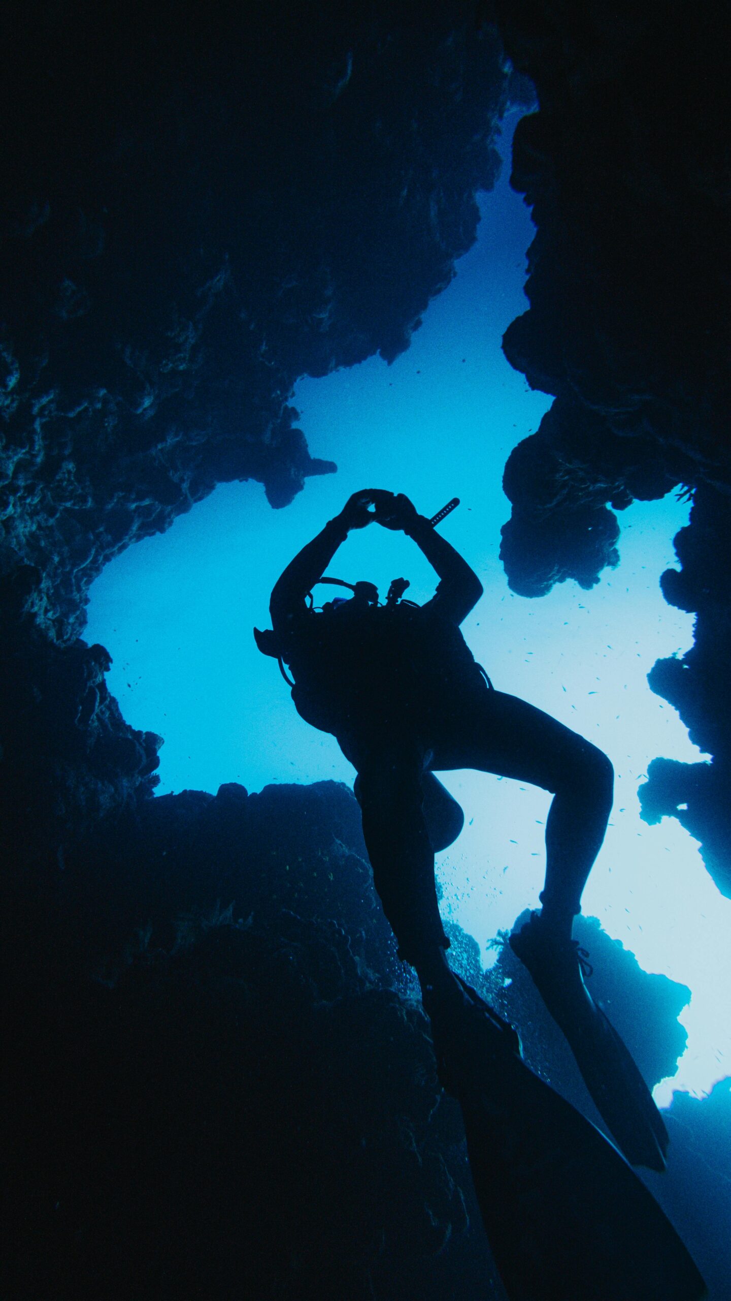 Silhouette of scuba diver exploring underwater cave